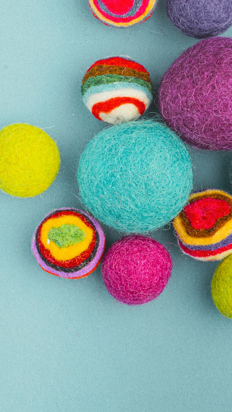 Bunte Filzwollkugeln auf hellblauem Untergrund.